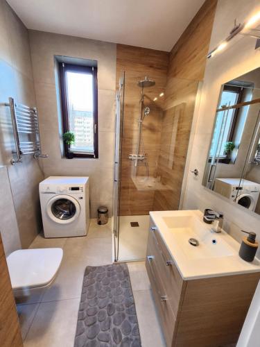 a bathroom with a shower sink and a washing machine at Premium Spire Apartment +parking in Warsaw