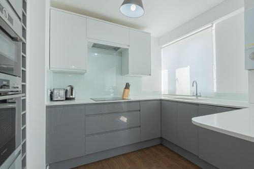 una cocina blanca con armarios blancos y fregadero en Charming 1 Bedroom Serviced Apartment in Camden, en Londres