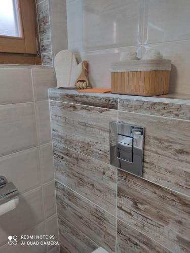 a bathroom with a wooden wall with a toilet paper dispenser at Kuca za odmor Milica in Vrnjačka Banja
