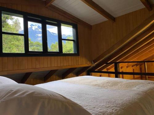 een slaapkamer met een bed in een kamer met ramen bij Casa Murta in Chaitén