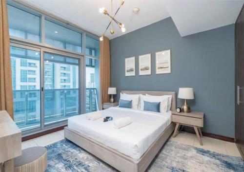 a bedroom with a large bed with blue walls and windows at Astonishing 1 Bedroom in Jumeirah Lake Towers in Dubai