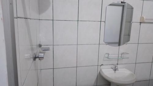 a white tiled bathroom with a sink and a mirror at Alojamiento Oruro in Riberalta