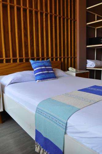 a bedroom with a bed with a blue pillow on it at Hotel Momotus Tuxtla - Desayuno opcional in Tuxtla Gutiérrez