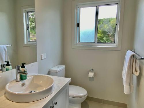 een badkamer met een wastafel en een toilet en 2 ramen bij Elevate Escape in Venus Bay