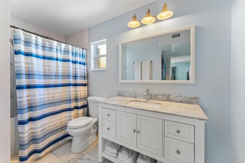 een badkamer met een wastafel, een toilet en een spiegel bij Tiki Blue in Cocoa Beach