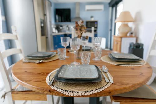 une table en bois avec des assiettes et des verres dans l'établissement Charmante maison proche plage, à Meschers-sur-Gironde