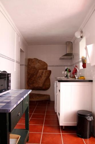 a kitchen with white cabinets and a red tile floor at Casa Toníca in Crato