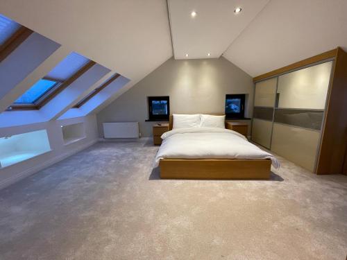 - une grande chambre mansardée avec un lit et des fenêtres dans l'établissement Executive Residence - Yorkshire Staycation Home, à Gomersal