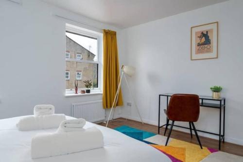 um quarto com 2 camas, uma cadeira e uma janela em Quiet 4 Bedroom House between Camden & Kings Cross em Londres