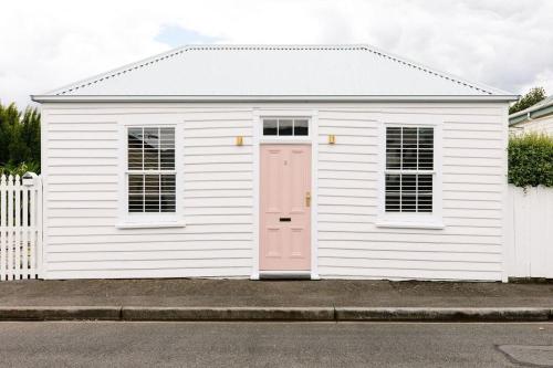 a small white building with a pink door at Good Soul Cottage in Invermay
