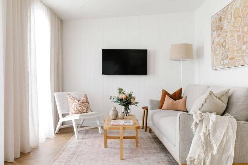 a white living room with a couch and a tv at Good Soul Cottage in Invermay