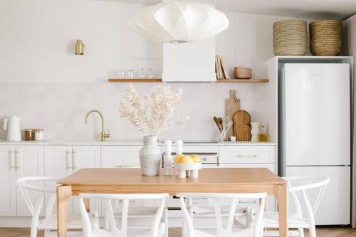 a kitchen with a wooden table with white chairs at Good Soul Cottage in Invermay