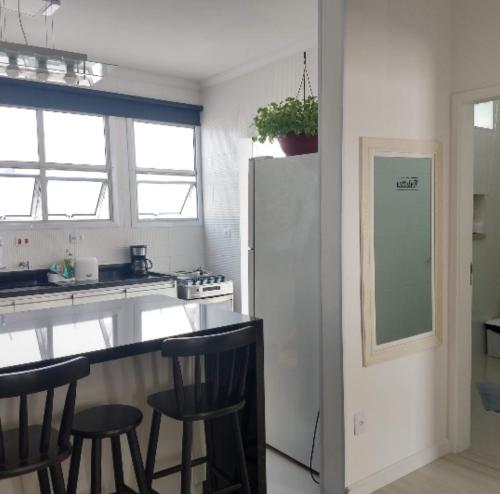 een keuken met een aanrecht met krukken en een koelkast bij Apt Guarujá Enseada lado praia FAN 1 dorm Tv Netflix Wi-Fi Ar até 5 pessoas in Guarujá