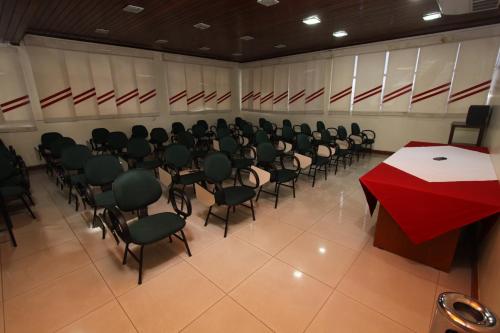 a conference room with a red table and chairs at Terrazzo Hotel in Campos dos Goytacazes