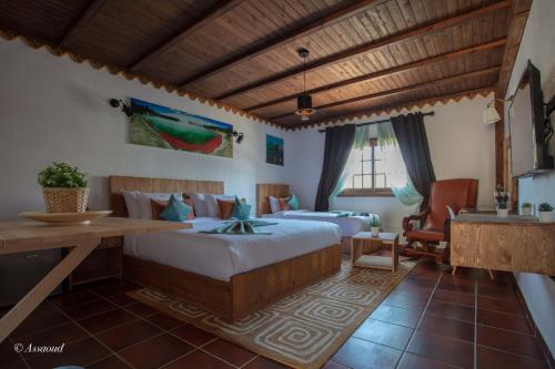 Un dormitorio con 2 camas y un escritorio en una habitación. en Hotel El Cortijo & SPA, en Chefchaouen
