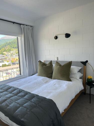 1 dormitorio con 1 cama grande y ventana grande en Wee Dram en Queenstown