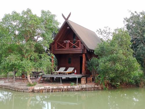 a log cabin by the water with a picnic table at LA'S FARMSTAY in Tây Ninh