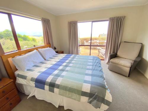 um quarto com uma cama, uma cadeira e janelas em Pohara's Kauri Lodge em Pohara