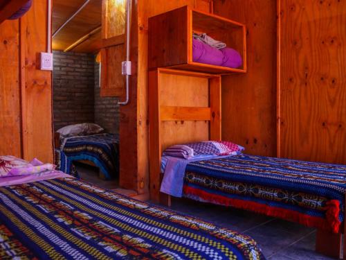 - 2 lits dans une chambre dotée de murs en bois dans l'établissement El Colibrí - Quebrada de la Luna., à Charbonier