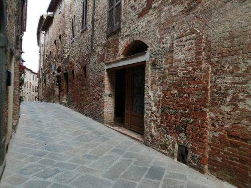 um beco com um edifício de tijolos e uma porta em Casa degli Angeli em Torrita di Siena