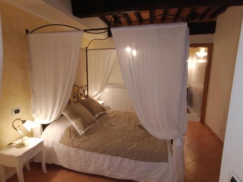 um quarto com uma cama de dossel e cortinas brancas em Casa degli Angeli em Torrita di Siena