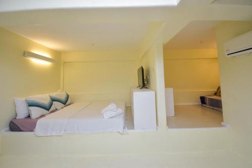 biała sypialnia z łóżkiem i telewizorem w obiekcie Babosam Apartments w mieście Boracay