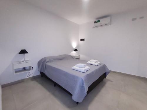 a white bedroom with a bed with two towels on it at Complejo Claret, Departamentos a metros de Sanatorio Allende y Hospital Privado Cerro in Córdoba