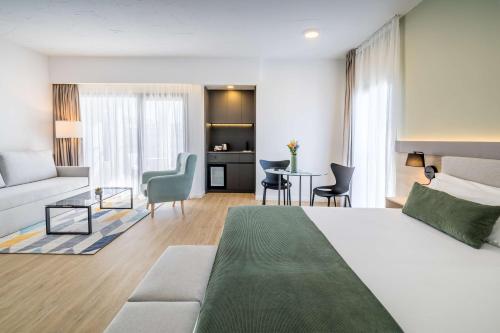 um quarto de hotel com uma cama e uma sala de estar em Occidental Puerto Banús em Marbella