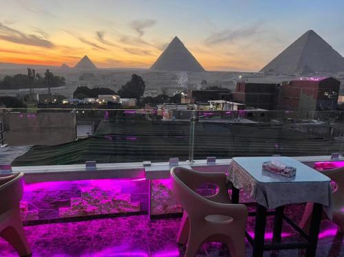 a table and chairs with a view of the pyramids at MAGIC Pyramids Hotel in Cairo