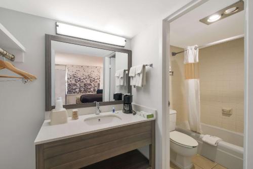 a bathroom with a sink and a toilet and a mirror at Rodeway Inn in Cleveland