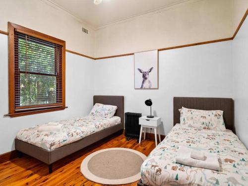 a bedroom with two beds and a table and a window at 'YANALEN COTTAGE' in Myrtleford