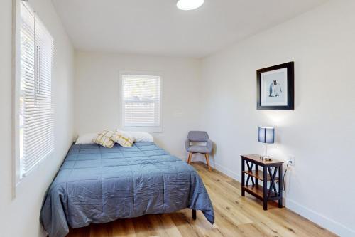 a white bedroom with a bed and a chair at Golden Coast Charmer in Riverside