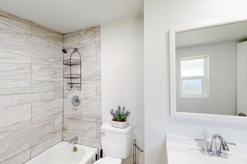 a white bathroom with a toilet and a sink at Golden Coast Charmer in Riverside