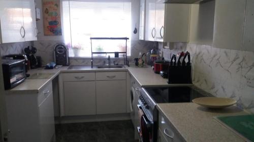 a kitchen with white cabinets and a stove top oven at Cosy furnished double room in a great quiet location walking distance to seaside and town in Kent