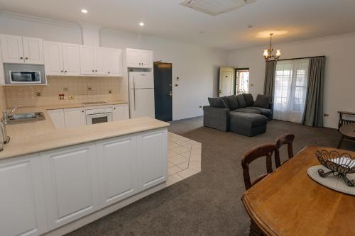 una cucina e un soggiorno con tavolo e divano di The Lawson Riverside Suites a Wagga Wagga