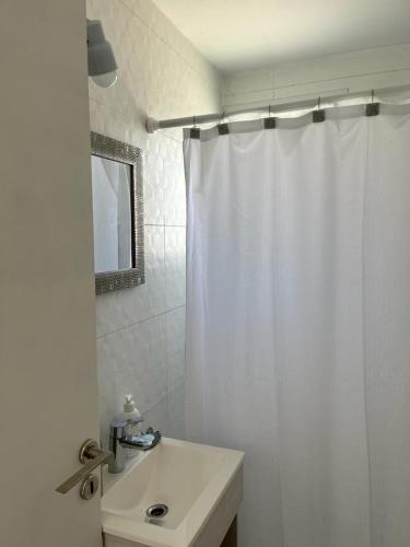 a bathroom with a white shower curtain and a sink at Casita Pirámides in Puerto Pirámides
