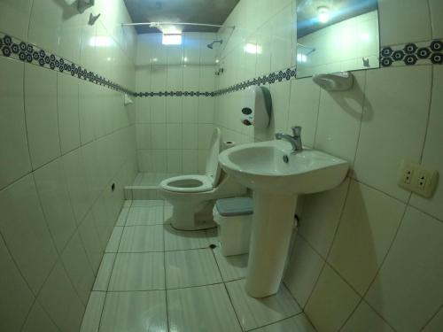 Baño blanco con lavabo y aseo en hostel Punoyork, en Puno