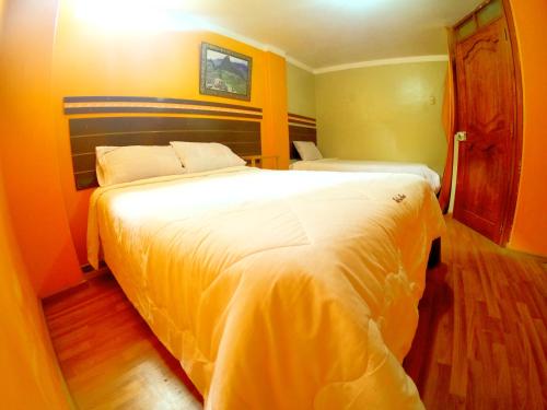 1 dormitorio con 1 cama blanca grande y paredes de color naranja en hostel Punoyork, en Puno