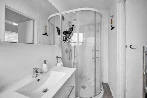 a white bathroom with a shower and a sink at New Plymouth Retreat: Beach, Port, Rock & City Nearby. in New Plymouth