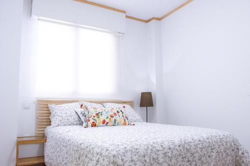 a white bedroom with a bed and a window at LA CASA DEL ORO in Zamora