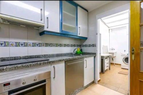 a kitchen with white appliances and blue cabinets at Bungalow adaptado, terraza muy grande y soleada. in Gran Alacant
