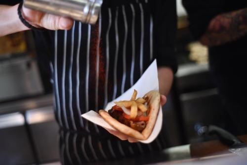 a person holding a hot dog with french fries at The Romanos, a Luxury Collection Resort, Costa Navarino in Romanós