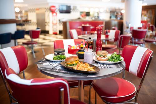 a table with two plates of food and two burgers and fries at The Romanos, a Luxury Collection Resort, Costa Navarino in Romanós