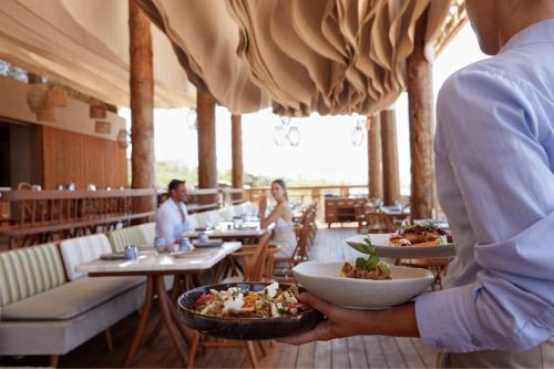 a man holding a bowl of food in a restaurant at The Romanos, a Luxury Collection Resort, Costa Navarino in Romanós