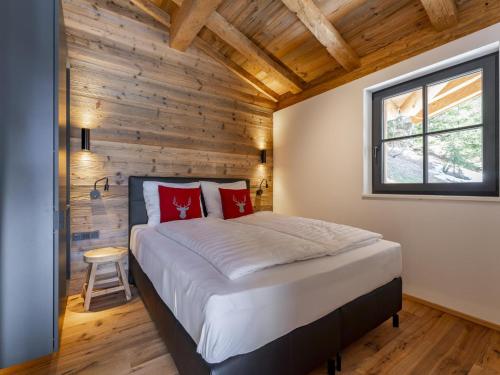 a bedroom with a bed and a wooden wall at Haus am Hang in Saalbach-Hinterglemm