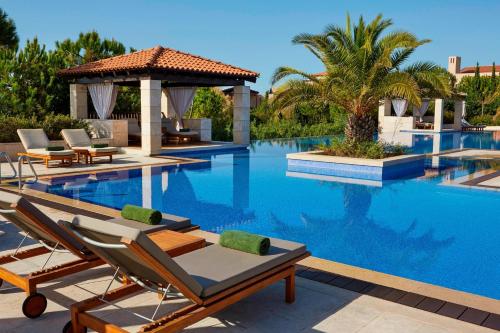 a swimming pool with chairs and a gazebo at The Romanos, a Luxury Collection Resort, Costa Navarino in Romanós
