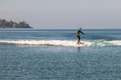 a man riding a wave on a surfboard in the ocean at The Romanos, a Luxury Collection Resort, Costa Navarino in Romanós