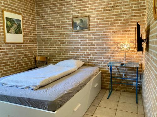 een bed in een kamer met een bakstenen muur bij Andrea 4pers workers only home in Anjum in Anjum
