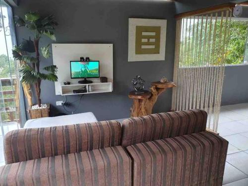 ein Wohnzimmer mit einem Sofa und einem TV in der Unterkunft Casa Azul da Cor do Mar in Paraty
