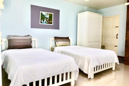 2 camas en una habitación con paredes azules en โรงแรมเจเอสเพลส, en Tha Bo